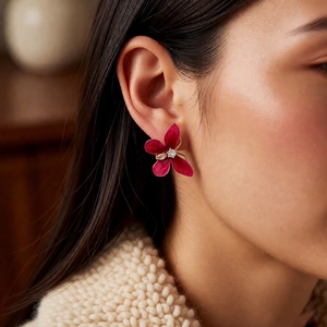 Gros plan de boucles d'oreilles pétales rouge foncé avec zircon et détails en émail doré