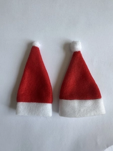Detail of two mini red non-woven Christmas hats with white plush trim on white background