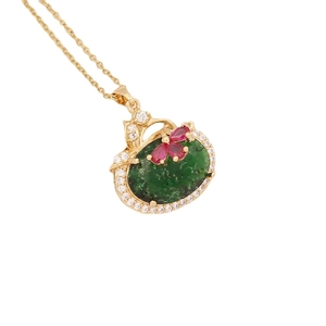 Golden necklace with emerald green stone and magenta floral zircon pendant on white background