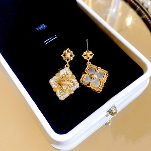 Détail de boucles d'oreilles fleuries avec zircons et nacre sur velours bleu