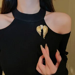 Elegant gold-tone angel wing brooch with sparkling rhinestones on a black garment