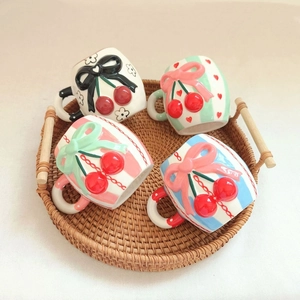 Ceramic cherry bow mugs set featuring colorful stripes and polka dots on a rattan tray