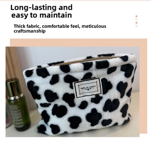 Detail of plush cow print pouch with heart patterns and Time to Party woven label