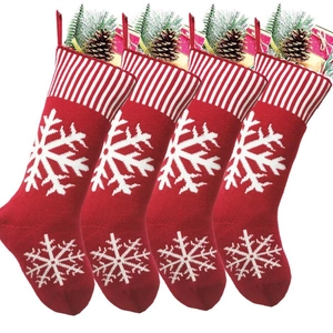 Set of four red knitted Christmas stockings with white snowflakes and gift fillers