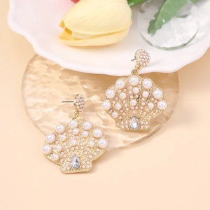 Macro shot of seashell-shaped earrings with faux pearls and crystals on glass