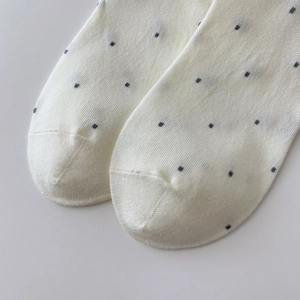 Detailaufnahme der weißen Baumwollsocken mit dunklen Punkten und feiner Strickstruktur