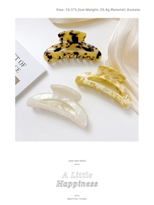 Detail view of acetate hair claw clips in tortoise and marble patterns on silk fabric