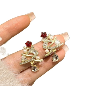 Golden Christmas tree earrings with pearls and rhinestones held in hand for details