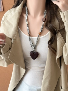 Detailed view of printed fabric scarf necklace with a dark heart-shaped wooden pendant