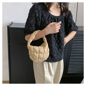 Detail view of a stylish quilted puffer cloud handbag, minimalist underarm bag design for women.