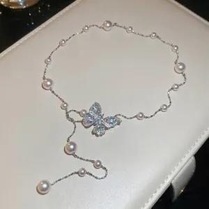 Elegante collana con farfalla in zircone e perle su portagioie in pelle beige