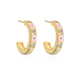 Detail of C-shaped gold hoop earrings with pink enamel evil eye and square zircon stones