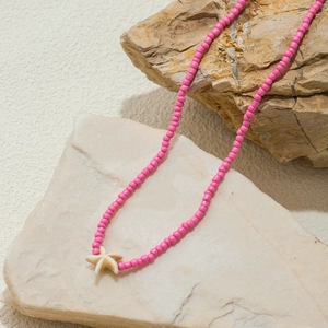 Macro detail of pink beaded necklace with starfish pendant on natural stone base