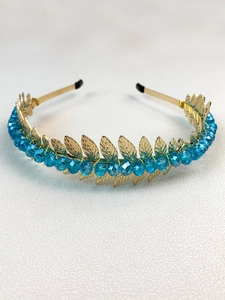 Detail of golden metal leaves and blue crystal beads on a handmade floral headband