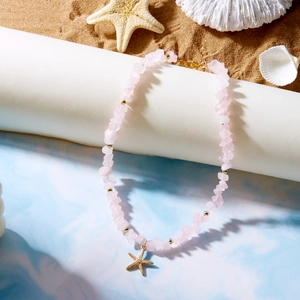 Pink stone beaded necklace with golden starfish pendant on beach themed background