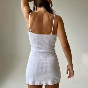 Detail view of the back of a white ribbed knit mini dress with thin shoulder straps