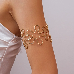 Close-up of golden wavy floral hollow arm cuff bracelet on a model's upper arm