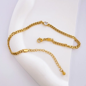 Detail of gold Cuban link bracelet with a sparkling round zircon and lobster clasp