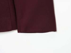 Detailed close-up of burgundy suit sleeve stitching and high-quality woven fabric texture
