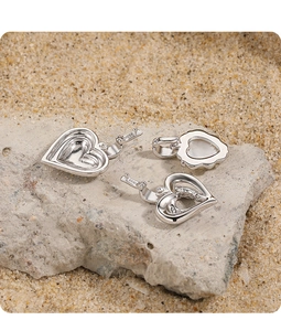 Detailed macro of S925 sterling silver heart and flower jewelry charms on a stone