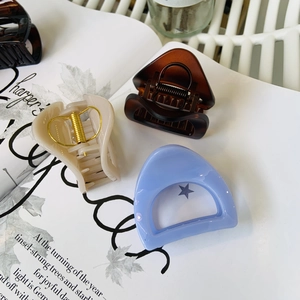 Three medium-sized triangular hair clips in brown, cream, and light blue on a magazine page