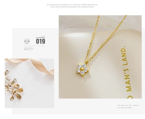Detail of flower pendant necklace with white zircons and gold chain on leather base