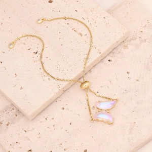 Close-up of golden butterfly bracelet with iridescent purple and pink pendants on stone