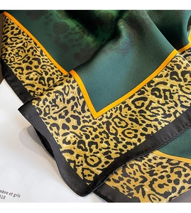 Gros plan détaillé d'un foulard en soie vert foncé avec bordure léopard et fleurs