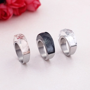 Three minimalist stainless steel rings with colorful glass stones on pink background