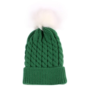 Close-up of green cable-knit winter hat texture with a fluffy white pom-pom detail