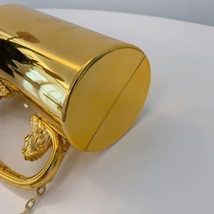 Detail of gold cylindrical acrylic bag featuring lion head handle and fine chain strap
