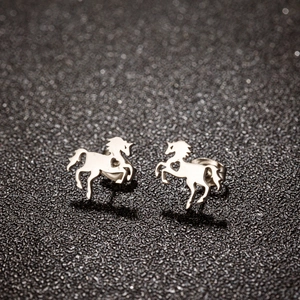 Macro view of silver unicorn stud earrings with hollow heart detail on black glitter surface