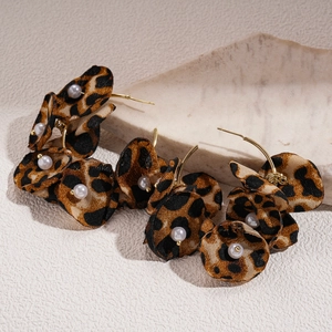 Macro detail of leopard print fabric flower earrings with faux pearl center and gold studs
