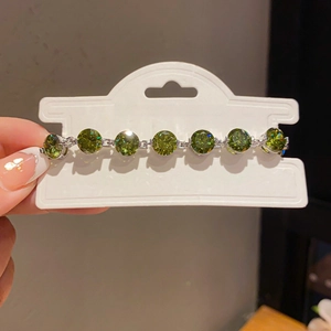 Detail of elegant silver bracelet featuring seven round-cut green zircons in prong setting