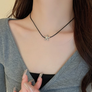 Close-up of silver starfish pendant with textured finish on a black cord necklace