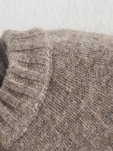 Close-up of the round neckline and ribbed knit texture on a beige wool cardigan