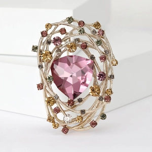 Close-up of bird nest brooch with large pink triangle gem and sparkling rhinestones