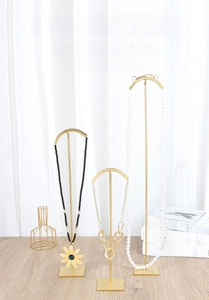 Detailed close-up of golden T-shape jewelry display stands with square bases for necklaces