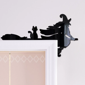Detailed view of black acrylic witch and cat silhouette corner decor on white door frame