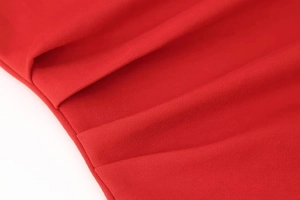 Detailed macro view of bright red knitted fabric with elegant vertical pleated texture