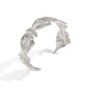 Detail of silver fish embossed patterns on a polished stainless steel open bangle
