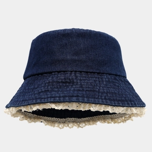 Détail d'un chapeau bob en jean bleu foncé avec bordure délicate en dentelle crème