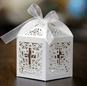 Detailed view of white laser-cut favor box with cross pattern and silk ribbon