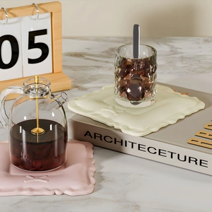 Detail of pink and cream bow coaster silicone mold under a glass teapot on marble table