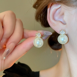 Détail d'une boucle d'oreille perle et zircon carré portée sur le lobe de l'oreille