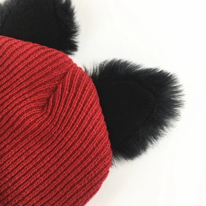 Close-up of red knit beanie featuring black fuzzy cat ears and rib texture detail