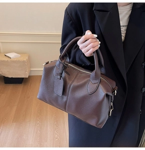 Close-up of a dark brown pebble leather Boston bag with a sturdy dual top handle design