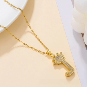 Close-up of gold J-letter pendant with crown and white zircons on a steel chain
