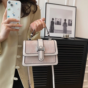 Detail of light pink floral embossed texture on a crossbody bag with silver metal lock