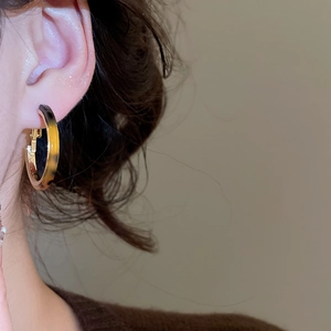 Detail of a C-shaped resin leopard print earring with gold trim on model's ear
